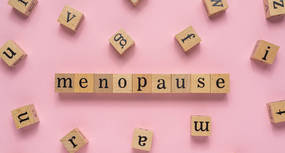 Menopause word on wooden block. Flat lay view on light pink background.