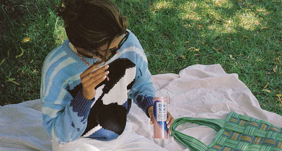 girl on a picnic blanket drinking DASH